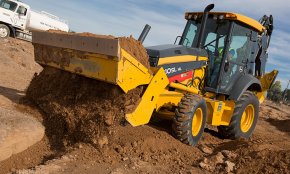 A backhoe loader unloads a bucket of dirt