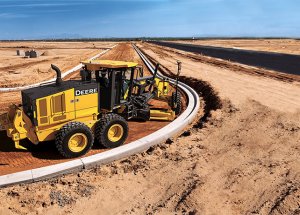 A John Deere motor grader levels ground for a road in the desert