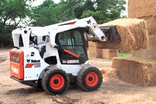 Bobcat S650 M2-Series skid-steer loader stacking bales of hay.