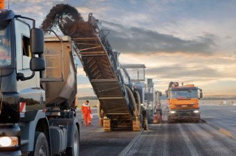 The large milling machine works through the pavement at a high advance speed.