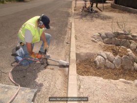 Tucson Concrete Cutting and Coring drilling 4-inch hole through curb. Drill is attached to hose to wet cut and reduce wear on drill bit.